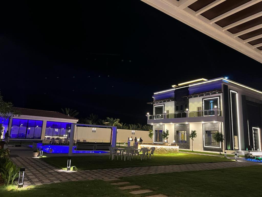 a house at night with blue lights on it at Calm Zone Luxury Private Pool 5BHK Villa in Al Ḩalāh