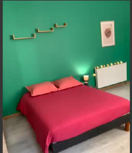 - une chambre avec un lit rouge et un mur vert dans l'établissement Studio Carcassonne Hyper Centre, à Carcassonne