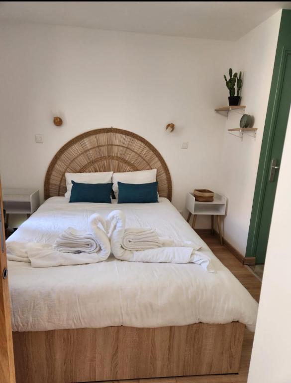 a bedroom with a large bed with white sheets and blue pillows at La cachette audomaroise avec sa terrasse in Saint-Omer