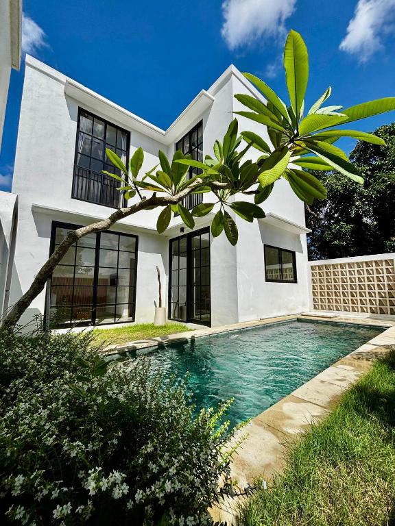 a white house with a swimming pool in front of it at Bukawa Residences Balangan in Jimbaran