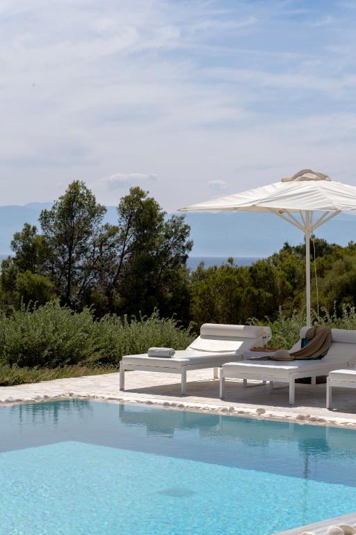a pool with two lounge chairs and an umbrella at Villa Seascape, Beachfront Living in the Greek Riviera Porto Heli in Porto Heli