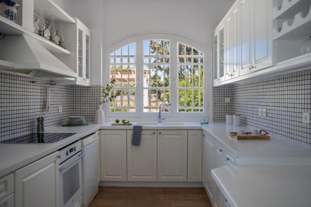 a white kitchen with a sink and a window at Villa Seascape, Beachfront Living in the Greek Riviera Porto Heli in Porto Heli