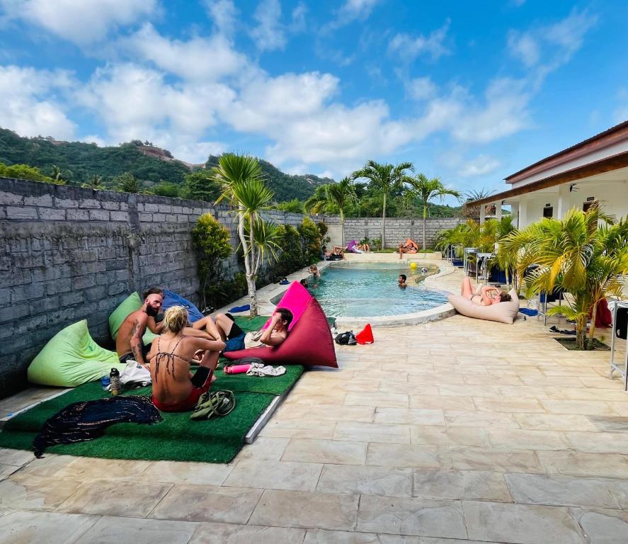 un gruppo di persone sdraiate intorno a una piscina in un resort di Jancoox Hostel a Kuta Lombok