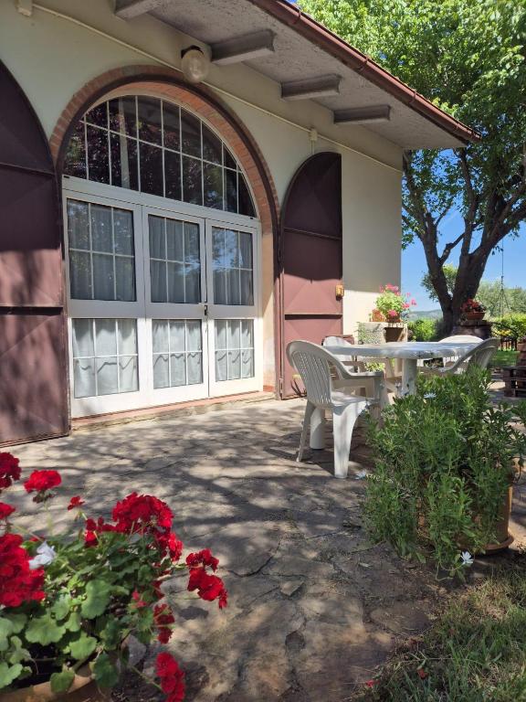 a house with a patio with a table and red flowers at Casa Alima in Suvereto