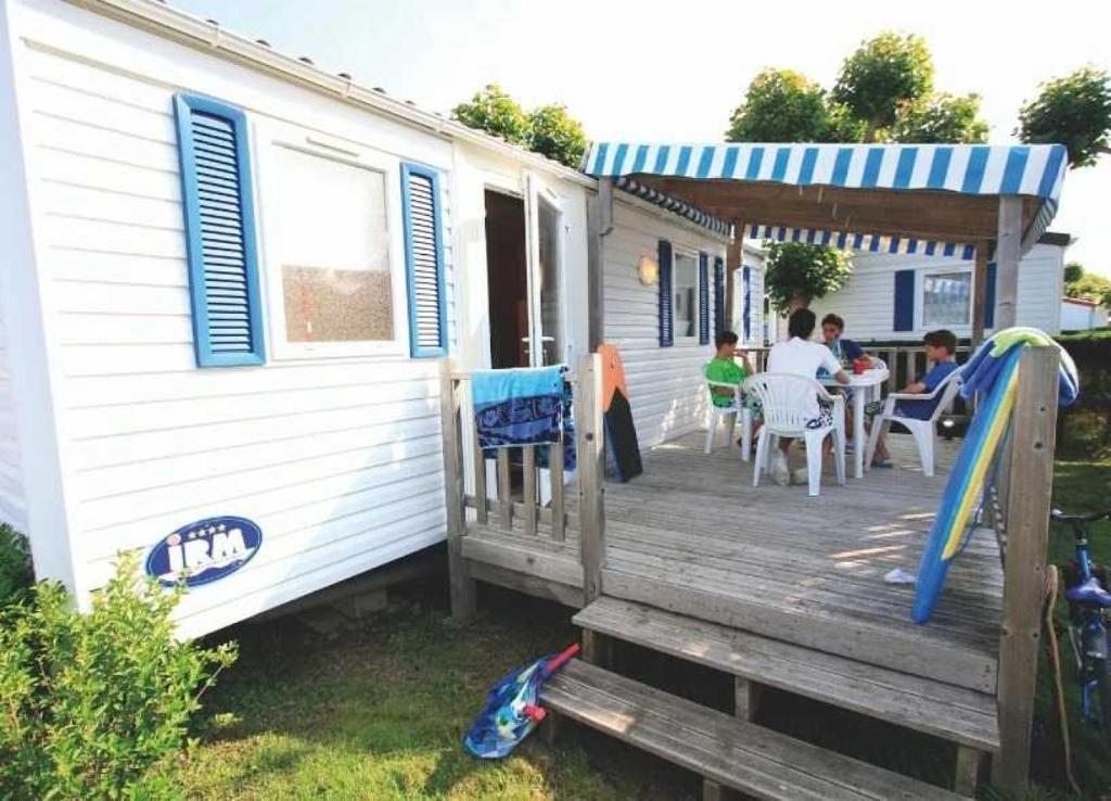 une maison dotée d'une terrasse avec des personnes assises dans l'établissement Camping - Piscine - ccagefg, à Portiragnes