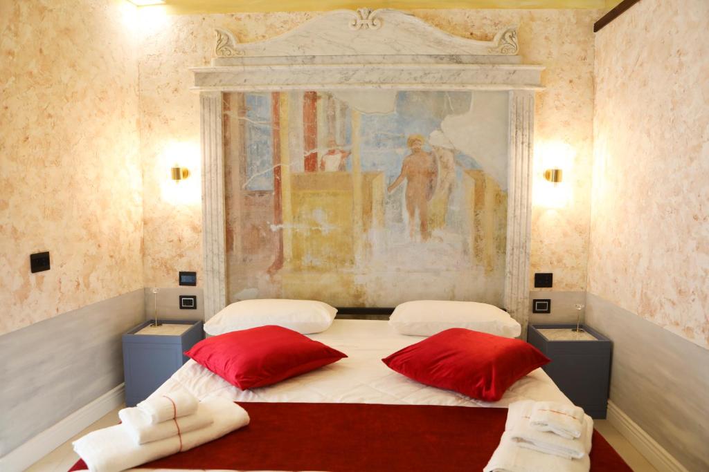 two beds in a room with two red pillows at Odeon Neapolis - Historic Suites in Roman Theater in Naples