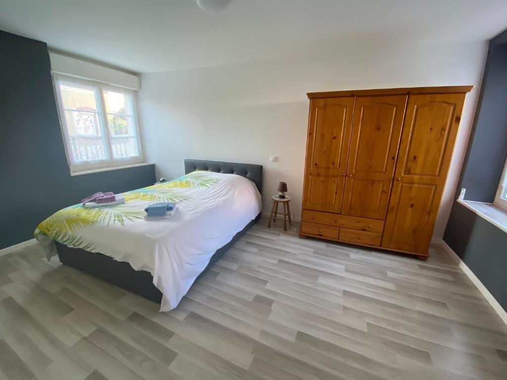 a bedroom with a bed and a wooden cabinet at p'tite maison in La Suze-sur-Sarthe