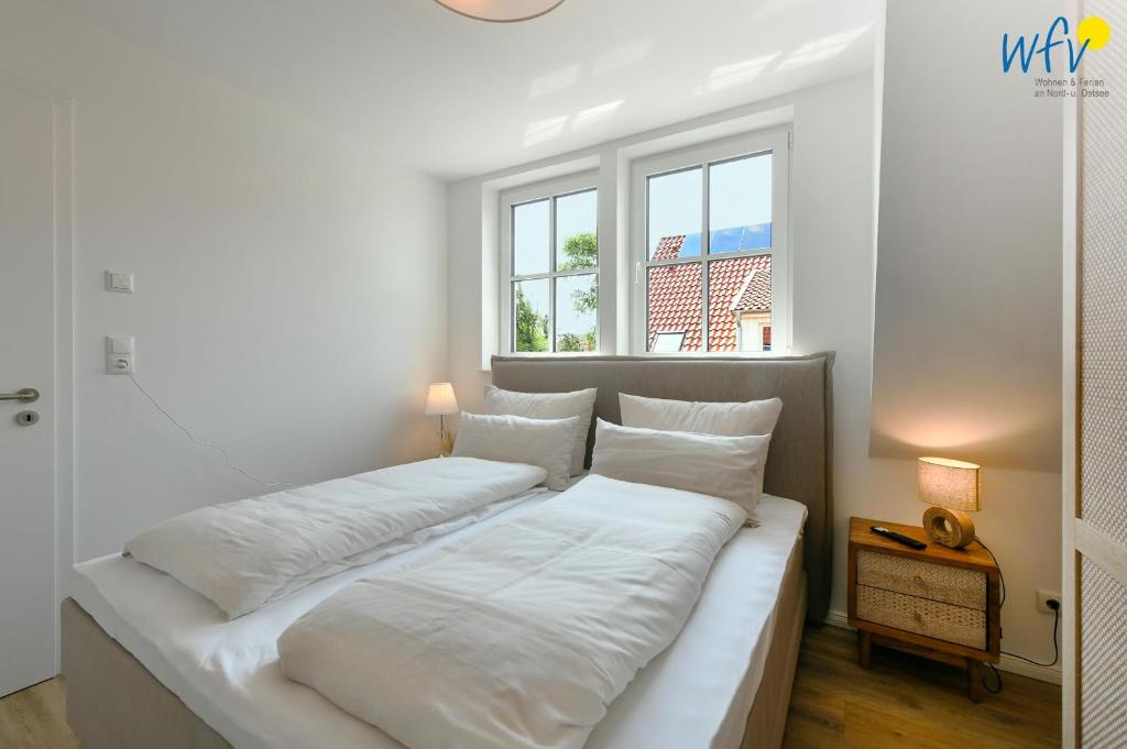 a large white bed in a room with a window at Haus Christine Ferienwohnung 4 in Langeoog