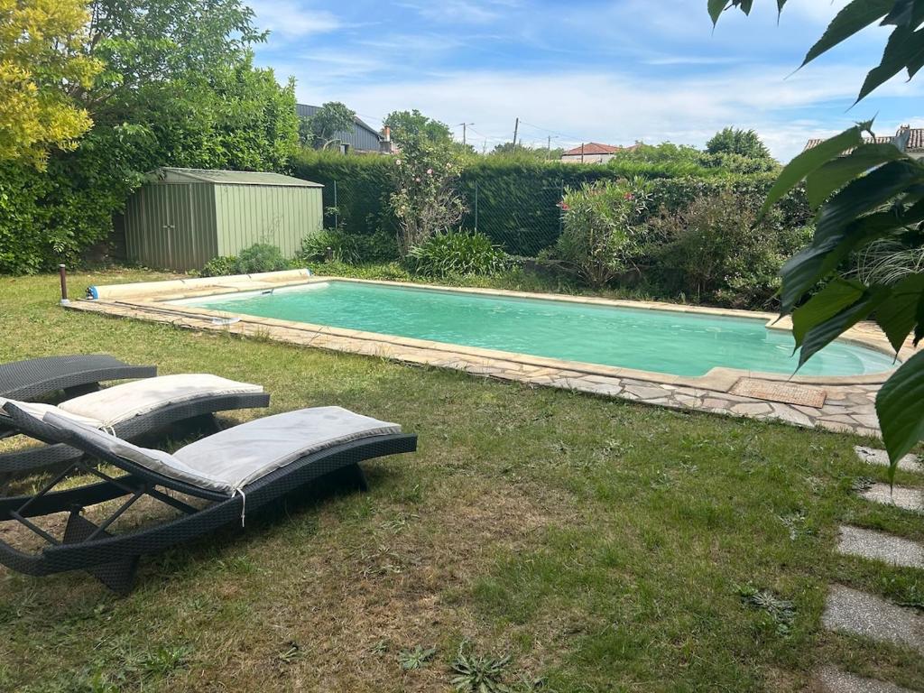 - une piscine dans une cour avec 2 chaises longues à côté dans l'établissement Spacieuse villa Les Alizées, à Montélimar