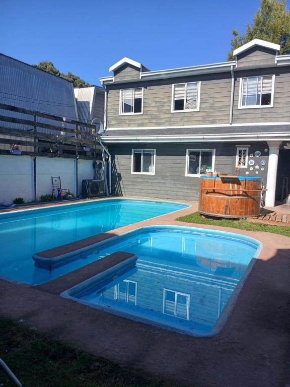 a large swimming pool in front of a house at Cabaña con tinaja de hidromasaje in Valdivia