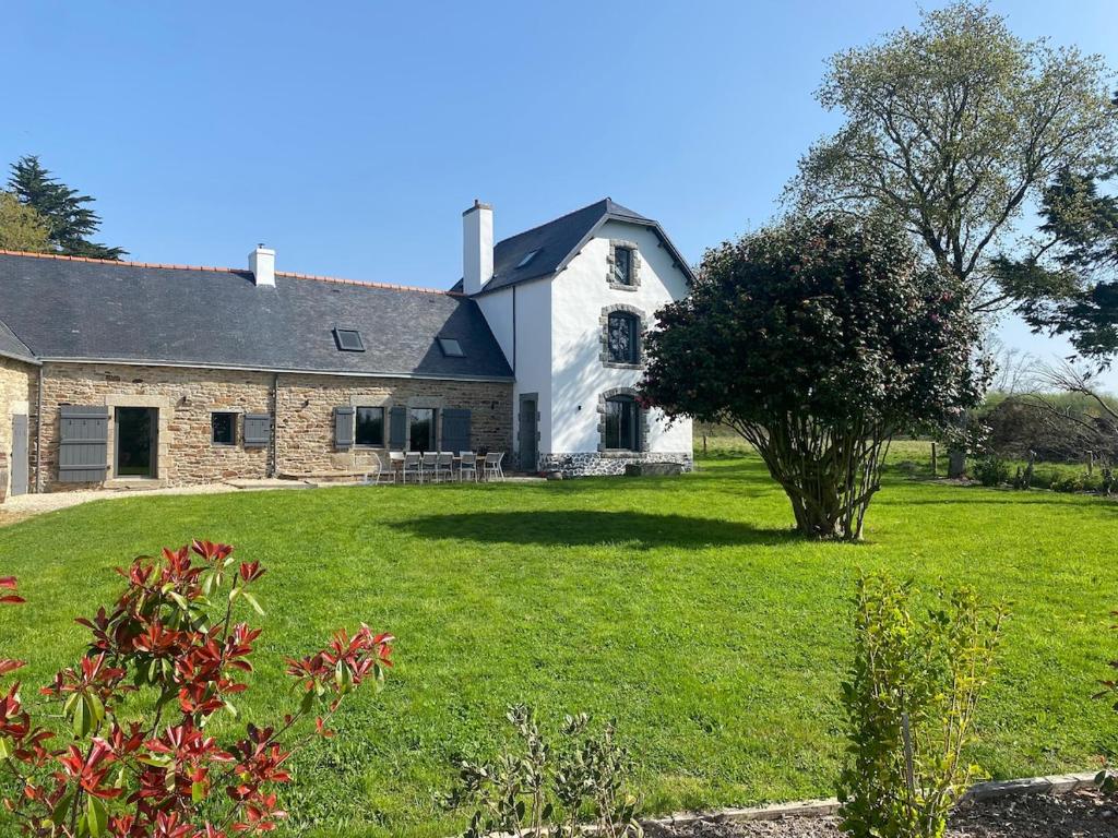 une vieille maison en pierre avec un arbre dans la cour dans l'établissement Domaine de Keryouen, à Trégunc