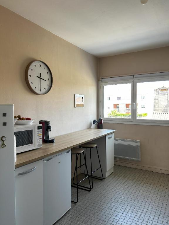 une cuisine avec un comptoir et une horloge au mur dans l'établissement Vacances a Biscarrosse entre lacs, ocean et confort, à Biscarrosse