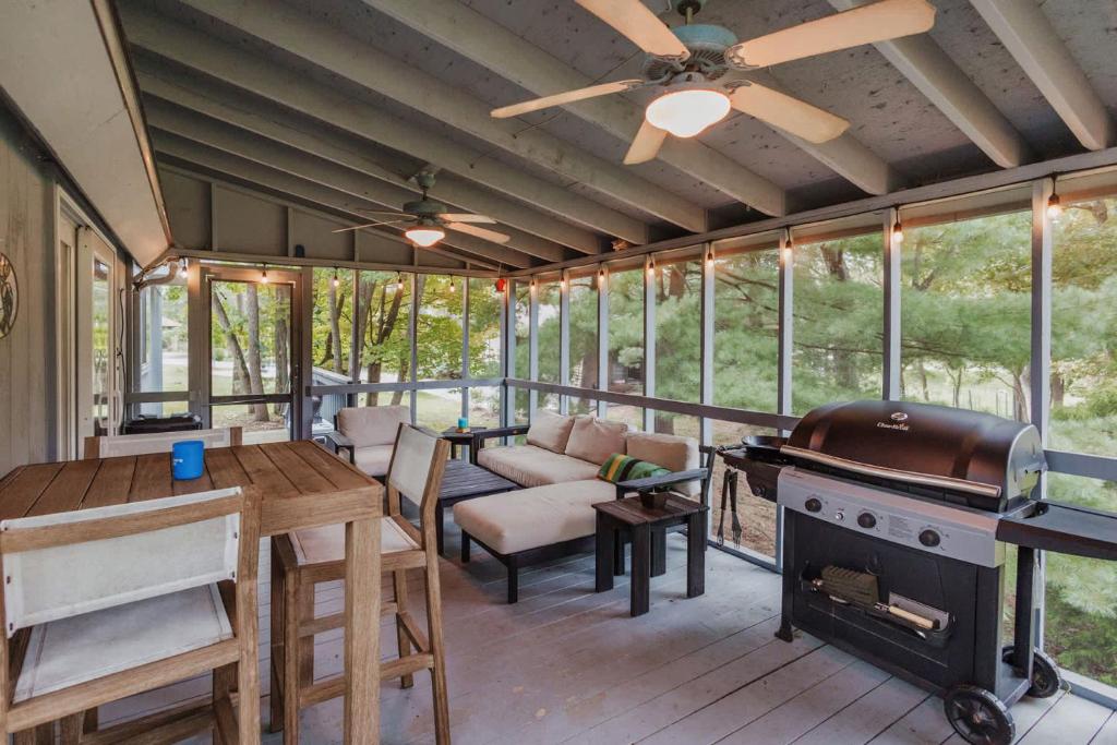 a screened in porch with a grill and a living room at Fireplace Fire Pit Covered Porch & Resort Access in Hedgesville