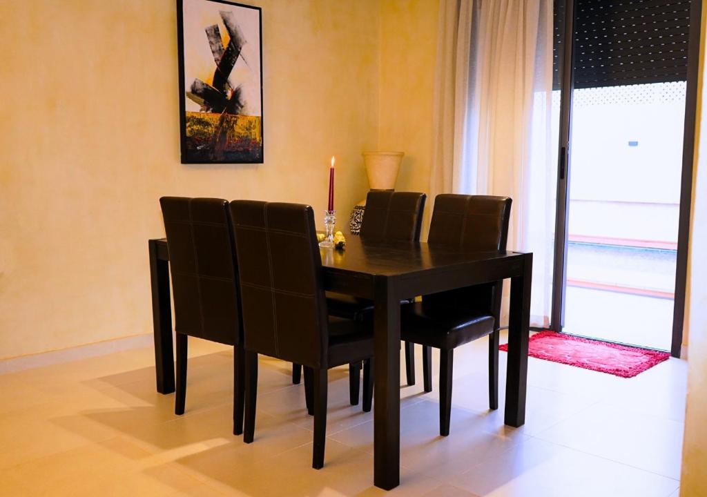 a dining room table with chairs and a candle on it at Villa Sable de Mirleft Luxury Apartment in Mirleft