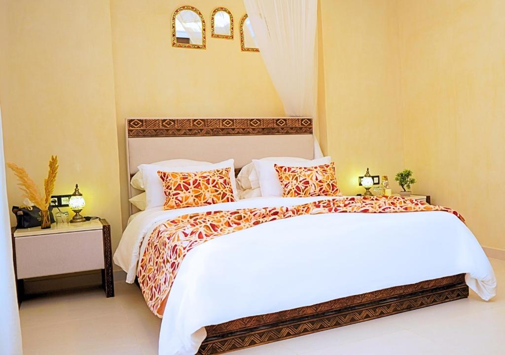 a bedroom with a bed with white sheets and orange pillows at Villa Sable de Mirleft Luxury Apartment in Mirleft