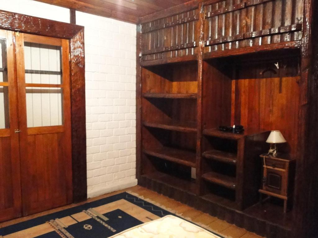 una habitación con estanterías de madera y una puerta en Cabana Do Vale Encantado, en Campos do Jordão