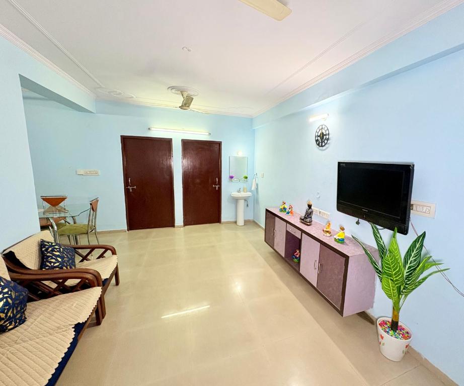 斋浦尔Highway access 2BHK, Trendy decor, VR & other water parks的客厅设有蓝色的墙壁和平面电视。