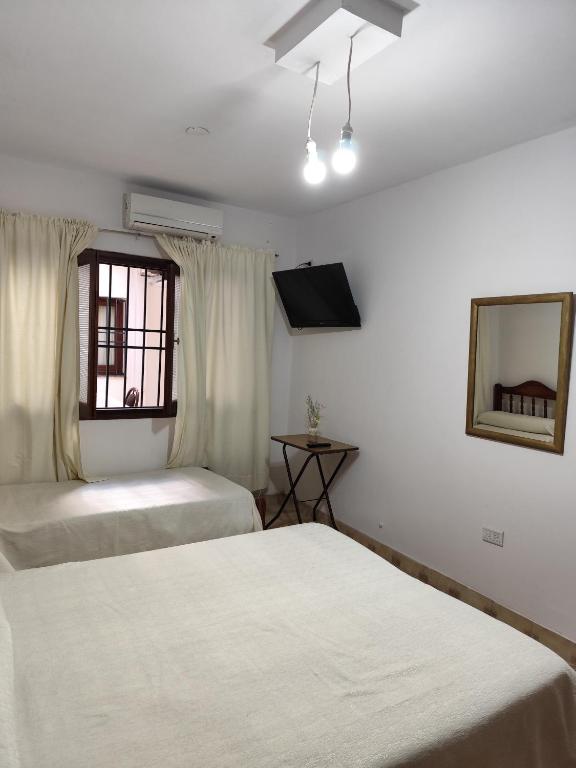 a bedroom with two beds and a mirror and a window at Cerro del sol, habitaciones privadas in Salta
