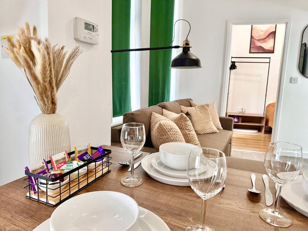 a dining room table with plates and wine glasses at Chic & Modern 2BR Apartment - Luxury Manchester Retreat in Manchester