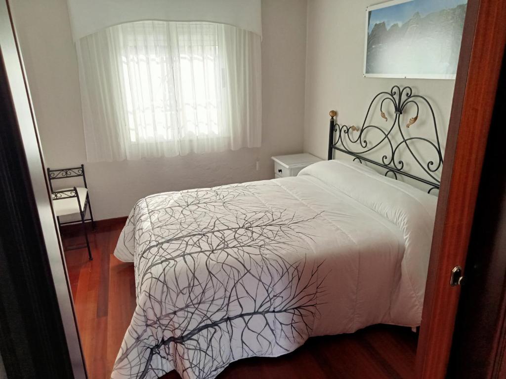 Un dormitorio con una cama blanca y una ventana. en el apartamento de zocas, en O Barqueiro