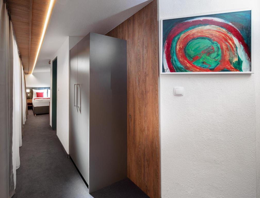 a hallway with a metal door and a painting on the wall at Hotel Höhlenstein in Tux