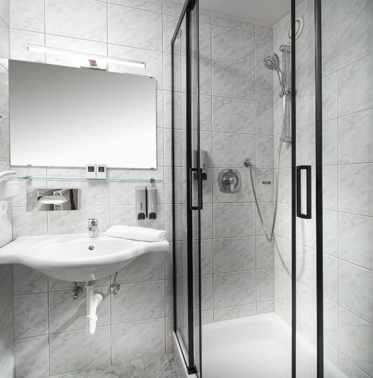 a white bathroom with a sink and a shower at Hotel Höhlenstein in Tux