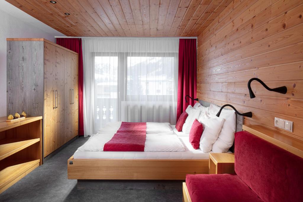 a bedroom with a large bed with red curtains at Hotel Höhlenstein in Tux
