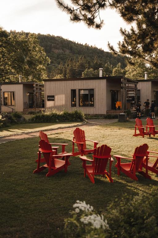 a group of red chairs and a table in the grass at Le 2800 du Parc in Shawinigan