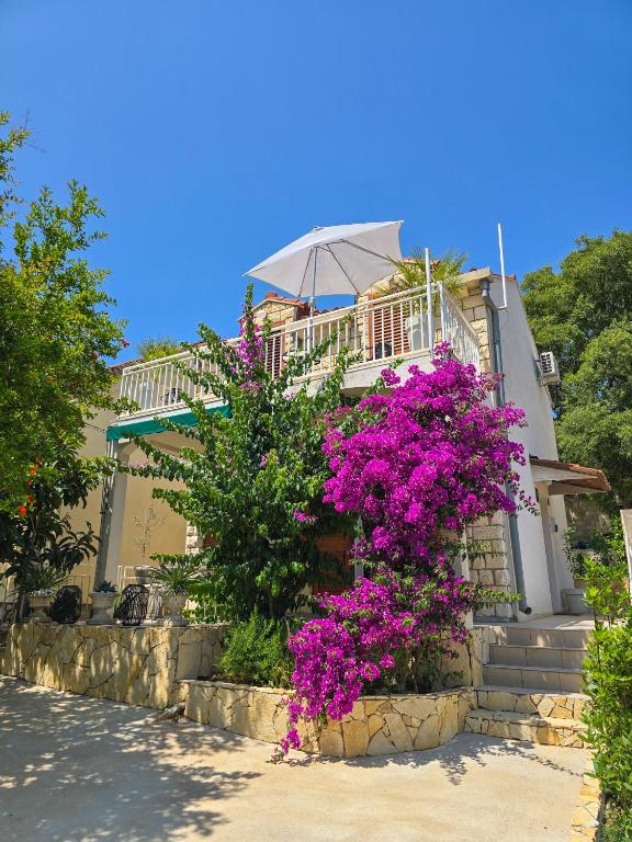 a house with purple flowers in front of it at Mala Kuća in Hodilje