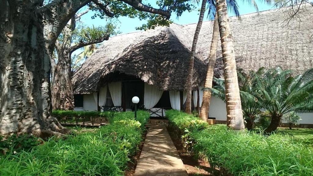 una casa con techo de paja y palmeras en Villa con baobab e piscina, en Malindi