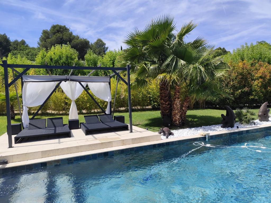 a pool with a gazebo and a palm tree at Chamarte villa piscine chauffées jardin clôturé Aix en Provence in Aix-en-Provence