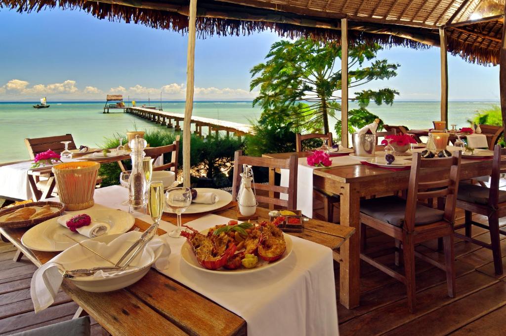 a restaurant with a table with food and a view of the ocean at Villas de Vohilava in Sainte Marie