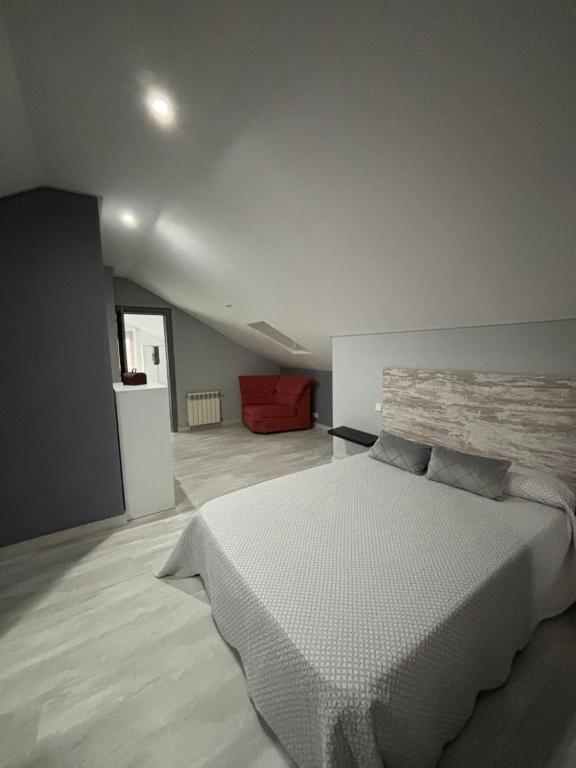 una camera con un letto bianco e un divano rosso di Apartamentos Redondo a Suances