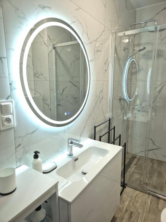 biała łazienka z umywalką i lustrem w obiekcie Brickstone Apartments Mabork w mieście Malbork
