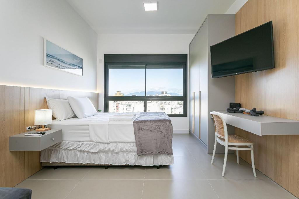 a bedroom with a bed and a desk and a television at Vista Mar | Piscina | WI-FI 600mb #CA79 in Florianópolis