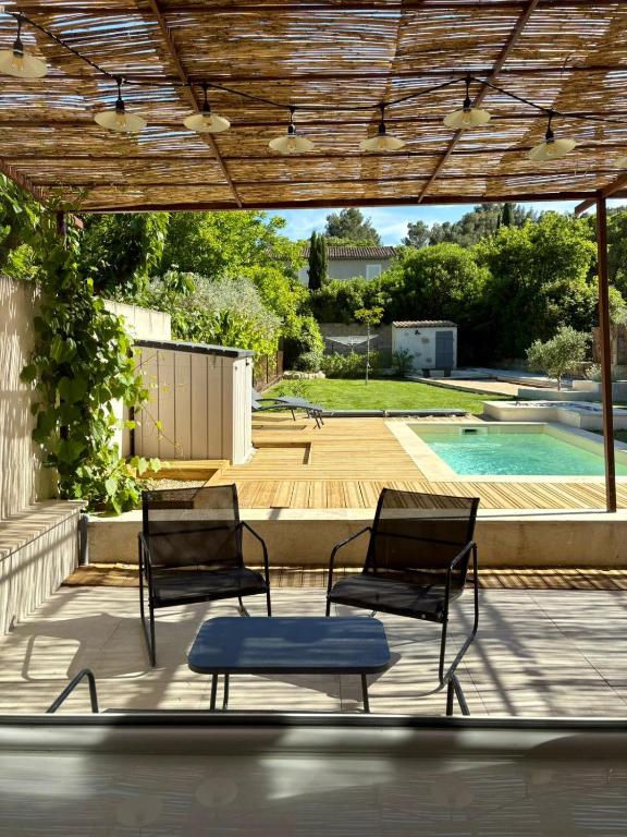 - 2 chaises et une table sur une terrasse avec piscine dans l'établissement Gîte Lou Galoubet, à Saint-Étienne-du-Grès