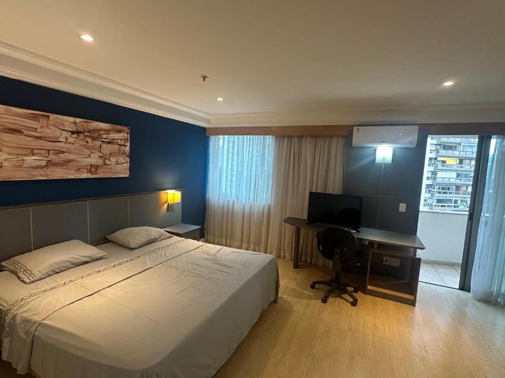 Un dormitorio con una cama y un escritorio con una computadora. en Mediterrâneo Fantastic, en Río de Janeiro