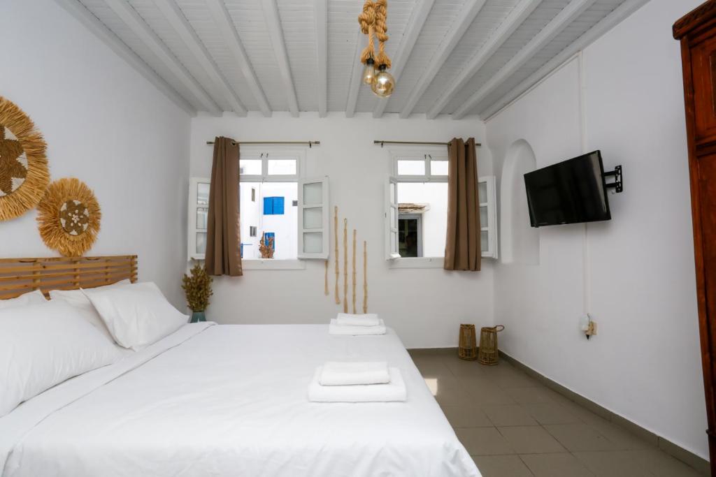 a bedroom with a large white bed and a tv at Magic holidays 111 in Tourlos