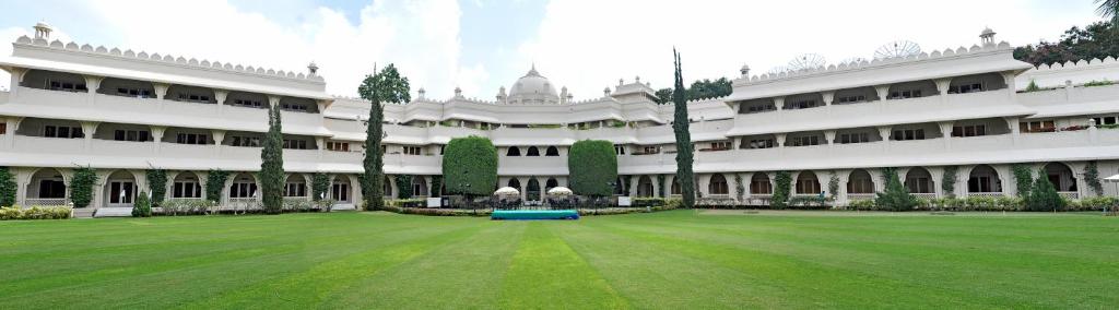 un grand bâtiment blanc avec une pelouse devant lui dans l'établissement Vivanta Aurangabad, Maharashtra, à Aurangabad