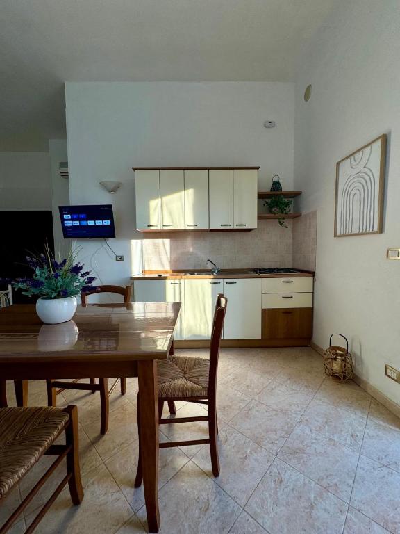La zona giorno di un monolocale con cucina attrezzata, tavolo da pranzo e TV a parete