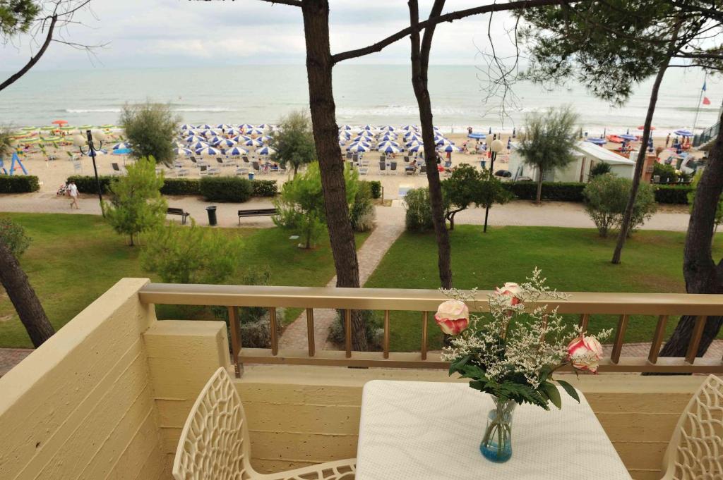 a vase of flowers on a table with a view of the beach at Hotel Abruzzo in Pineto