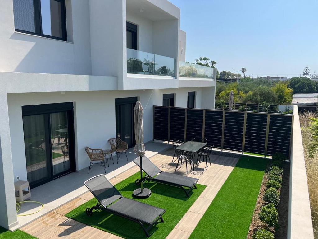 a balcony of a house with chairs and a lawn at Luxe benedenwoning Nula Kos in Kos