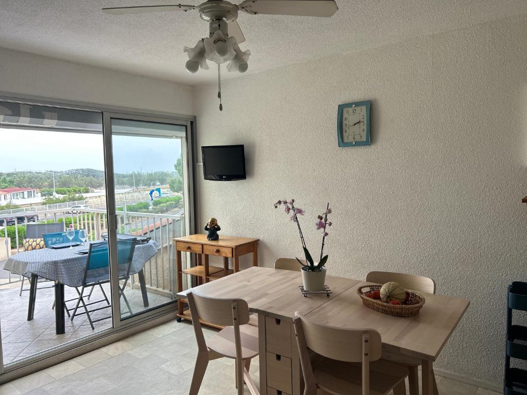 une salle à manger avec une table et une vue sur une terrasse dans l'établissement Au balcon de la mer, appartement à Marseillan plage, à Marseillan