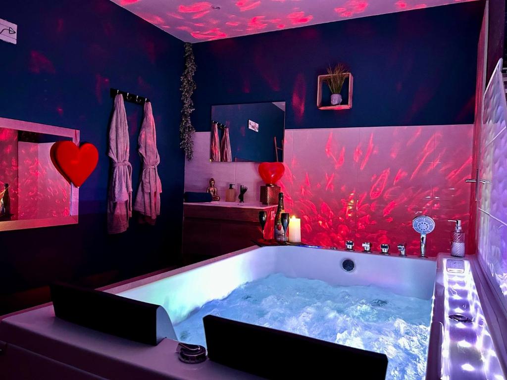 une salle de bain avec une grande baignoire avec un plafond rouge dans l'établissement Vénus - Maison de charme, zen avec SPA, à Plouray