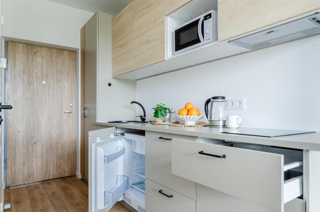 een keuken met witte kasten en een magnetron bij Nemunas A respite Studio 8 in Druskininkai