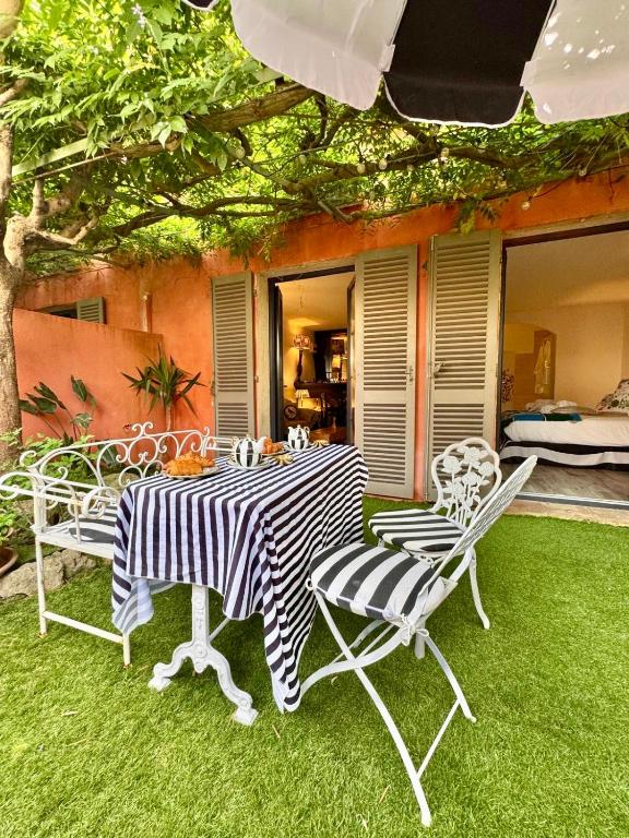 une table et des chaises sur une cour avec de l'herbe dans l'établissement Villa Romana, à Saint-Tropez
