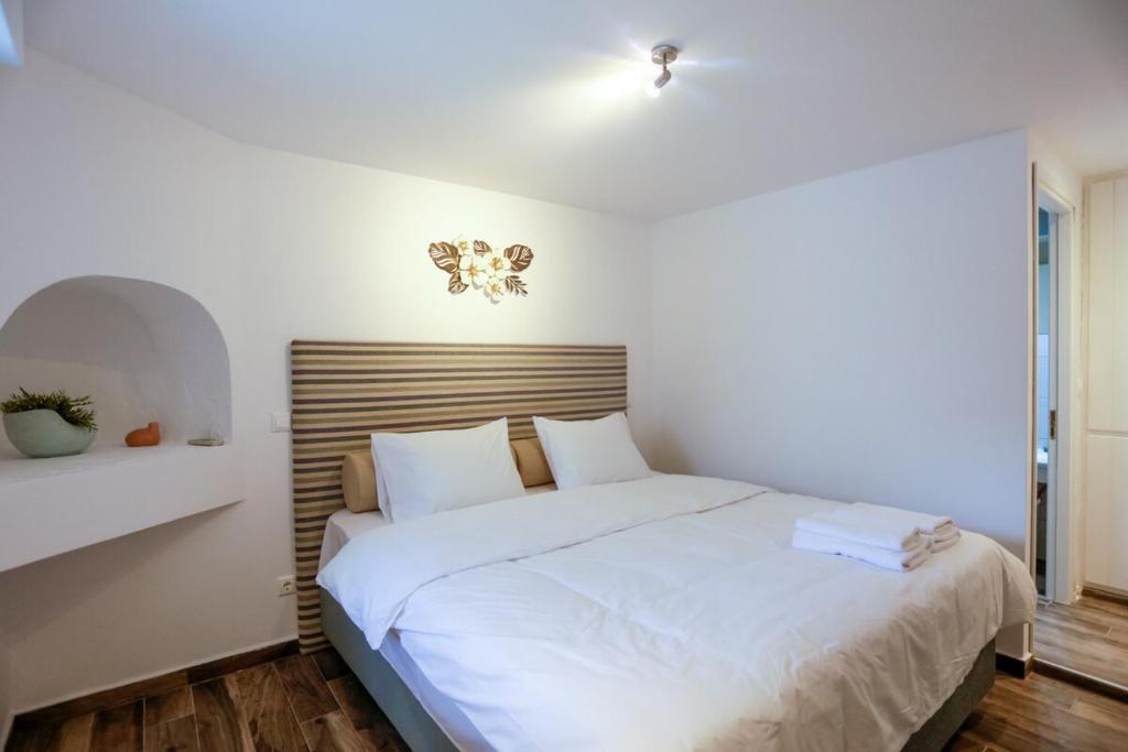 a bedroom with a white bed with a wooden headboard at Magic Holidays 444 in Mýkonos City