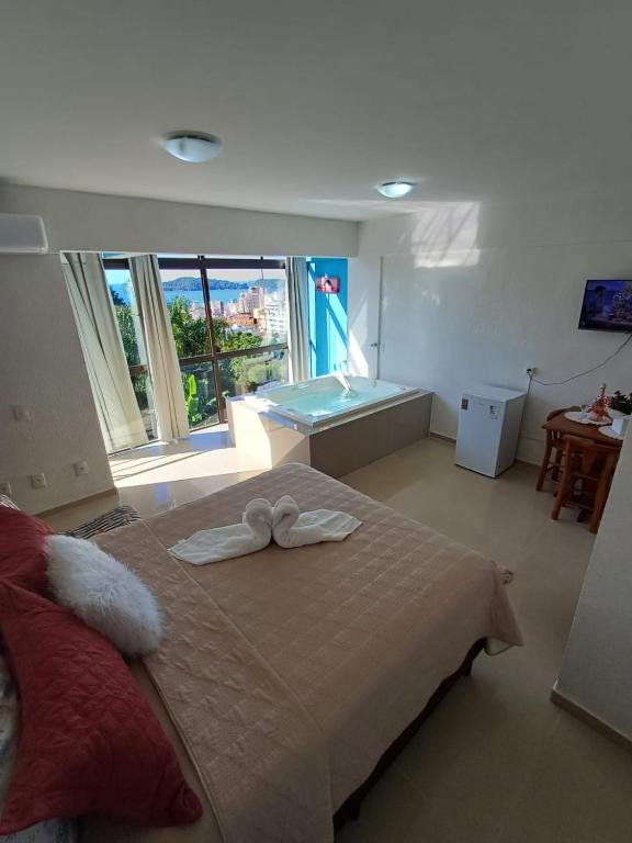 a bedroom with a bed and a tub and a window at Suíte Atlântica com banheira de hidromassagem in Bombinhas