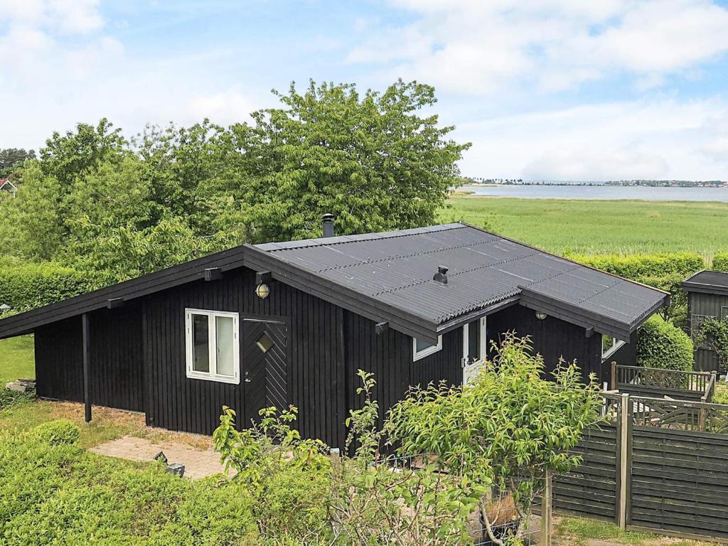 a black shed with a solar roof in a field at 4 star holiday home in Jægerspris in Jægerspris