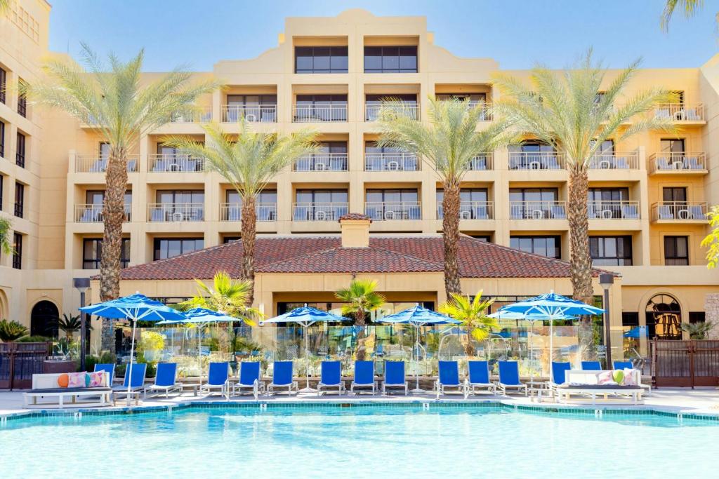 a hotel with a pool and chairs and palm trees at Renaissance Palm Springs Hotel in Palm Springs